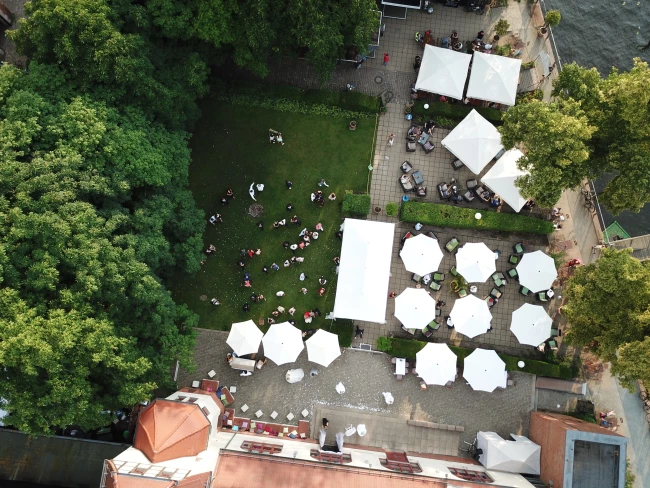 Drohnenaufnahme auf den Garten mit Schirmen und Zelten