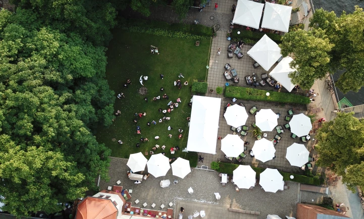 Drohnenaufnahme auf den Garten mit Schirmen und Zelten