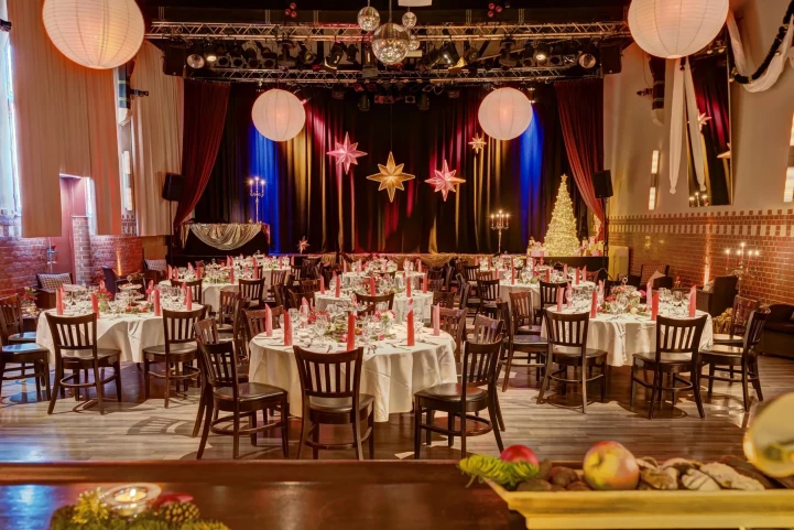 saal eingedeckt mit runden tischen für weihnachten